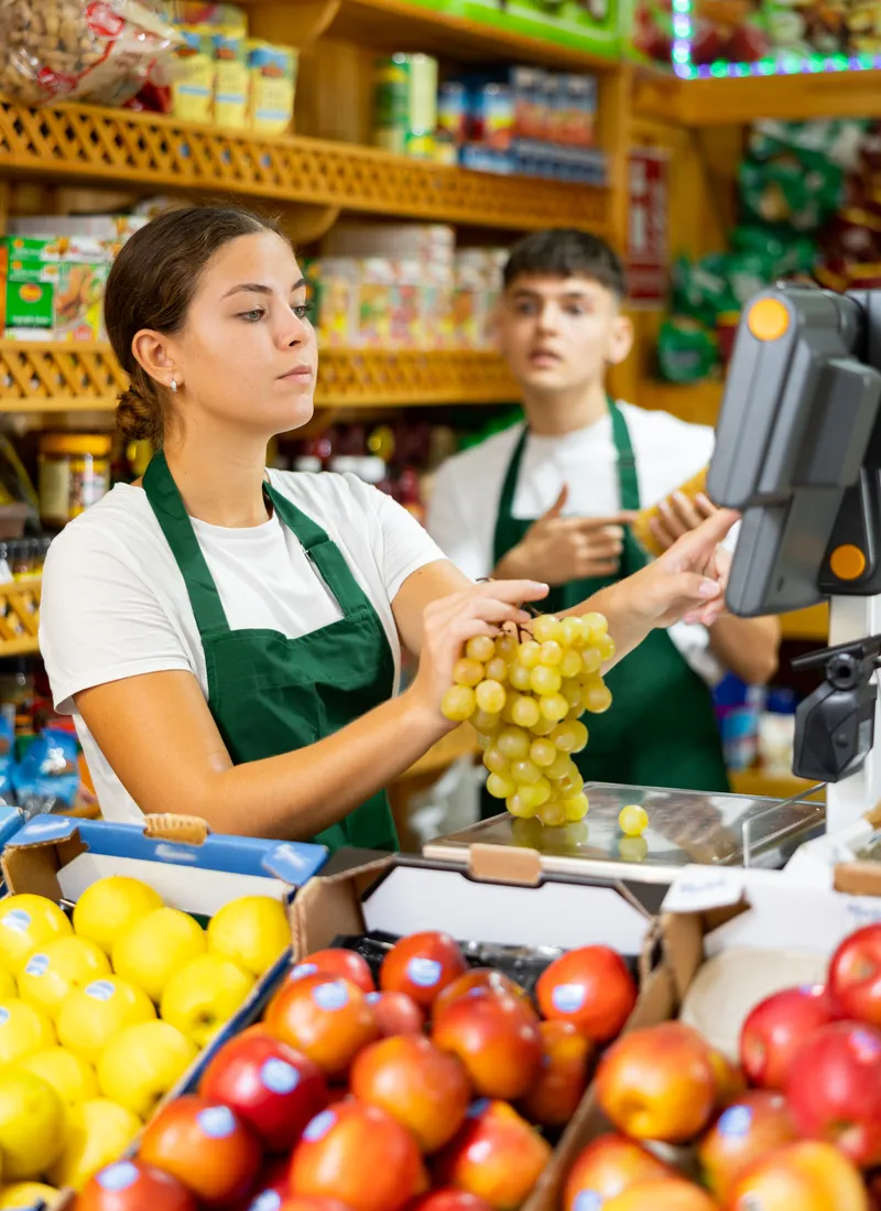 Mujer atendiendo un local de barrio, mostrando una actitud amigable en un ambiente seguro de trabajo.