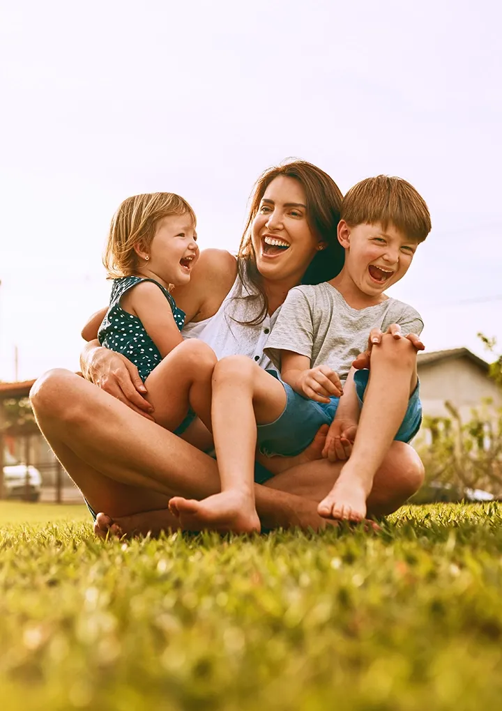 Una familia sonriente se relaja en el césped del parque de su hogar, compartiendo un momento de tranquilidad.