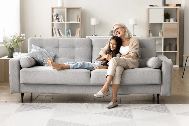Mujer y una niña sentadas en un sofá en el living de su casa, disfrutando de un momento juntas en un ambiente seguro y acogedor.