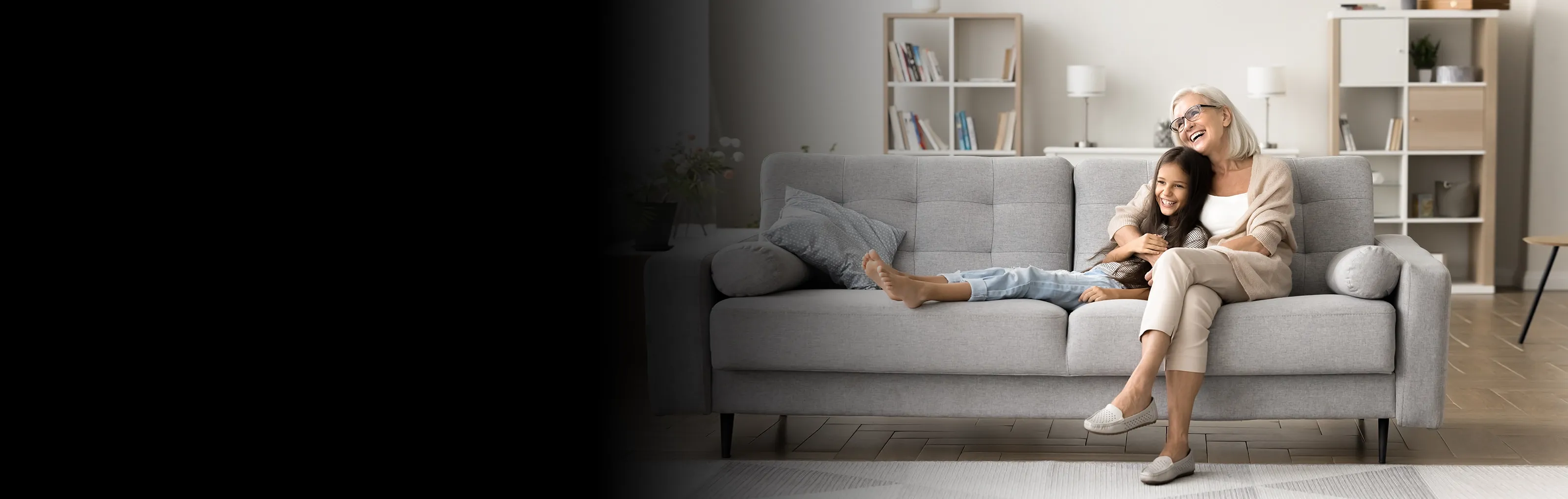 Mujer y una niña sentadas en un sofá en el living de su casa, disfrutando de un momento juntas en un ambiente seguro y acogedor.