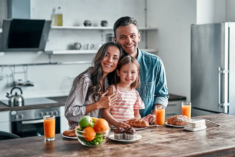 Familia compartiendo un desayuno en la cocina, se percibe un ambiente cálido y seguro.